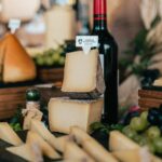 a table topped with lots of cheese and a bottle of wine